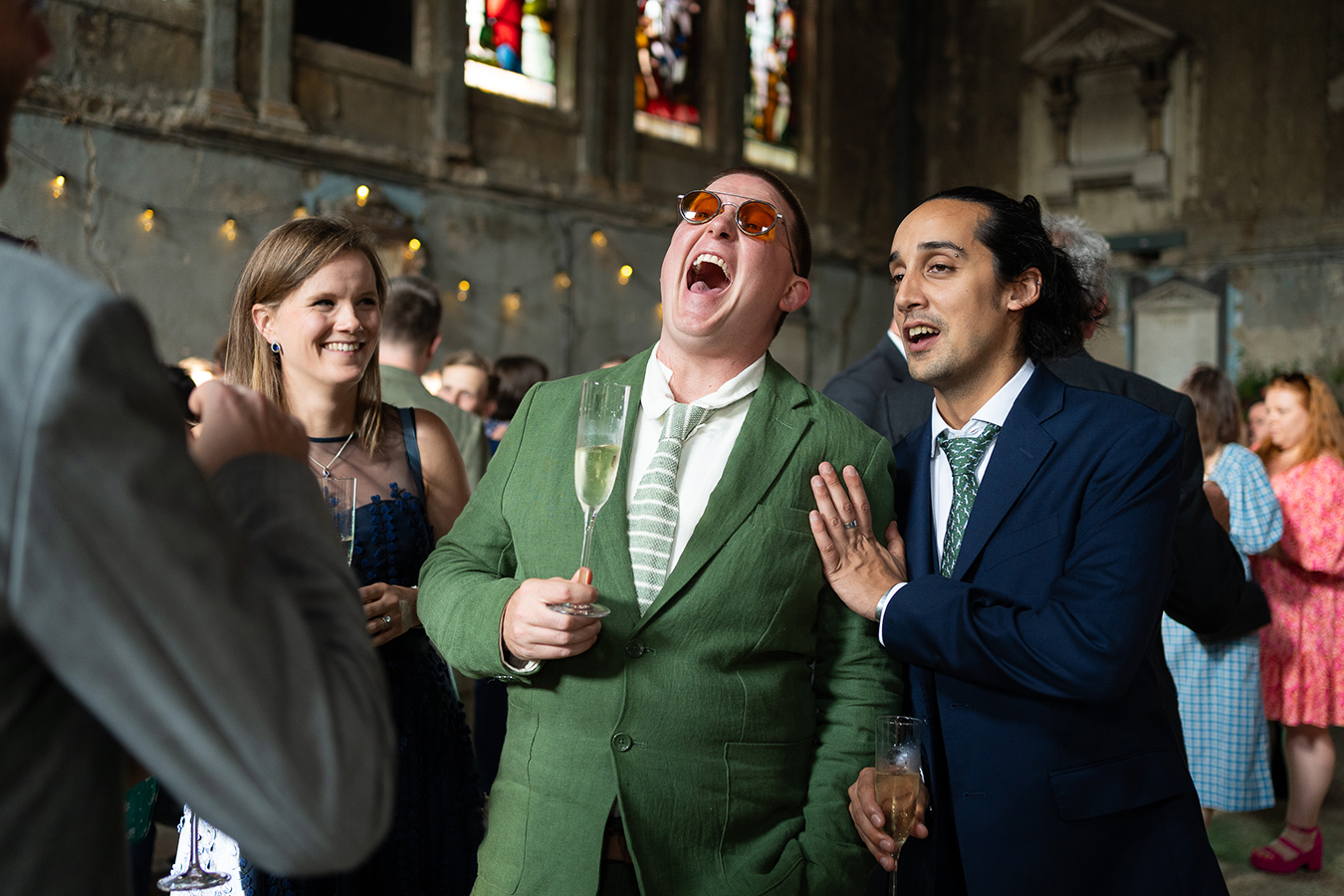documentary wedding photographer in london captures wedding guests laughing hysterically during wedding reception