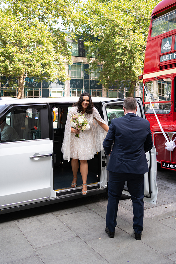 bride and groom exit white taxi on their intimate wedding at the Old Marylebone Town Hall
