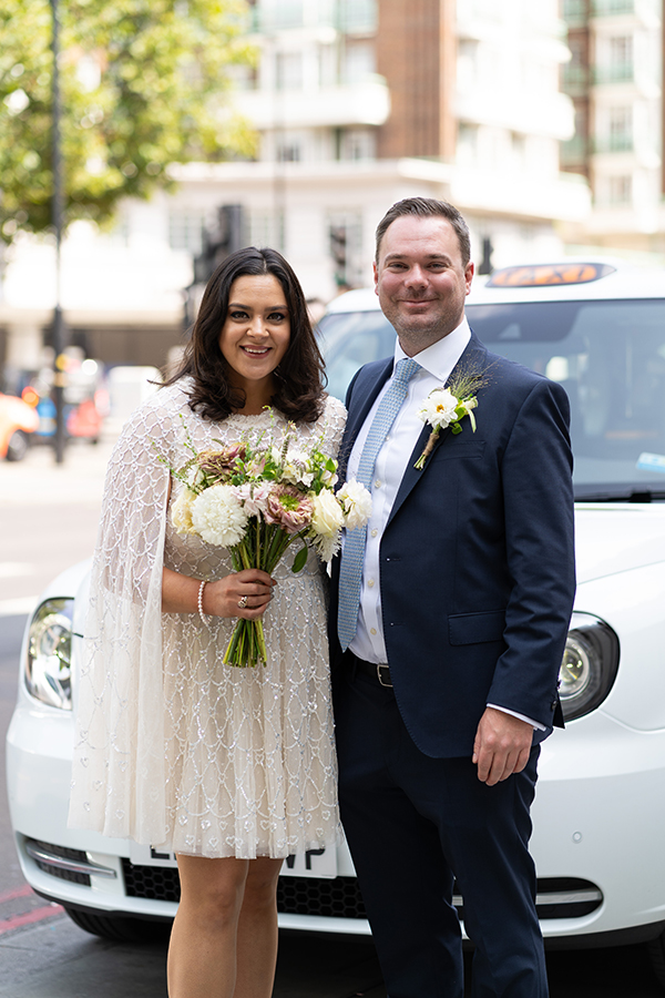 bride and groom standing in front of white cab